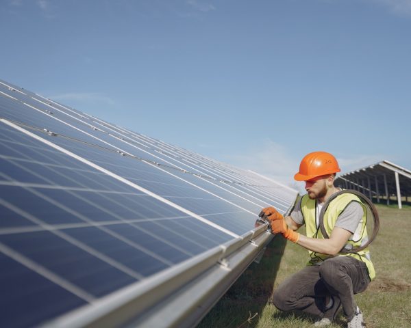 Male worker with solar batteries. Man in a protective helmet. Installing stand-alone solar panel system.