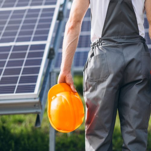 Man worker in the firld by the solar panels